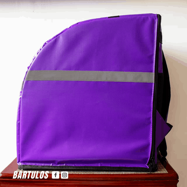 a purple bag is sitting on a wooden table with bartulos written on it