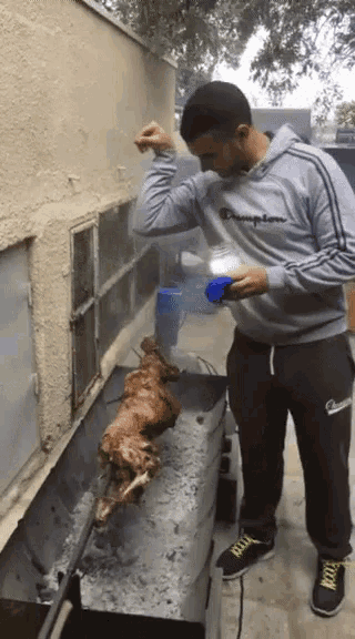 a man wearing a champion sweatshirt is cooking a chicken