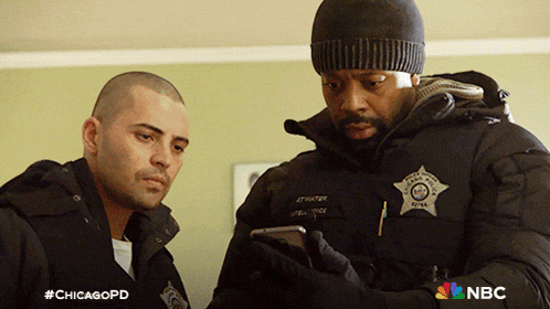 two police officers are looking at a cell phone with the hashtag #chicagopd on the bottom