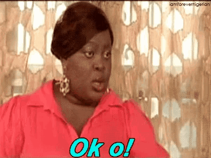 a woman in a red shirt is making a funny face and saying ok oi .