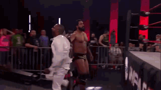 a man in a white shirt is standing next to another shirtless man