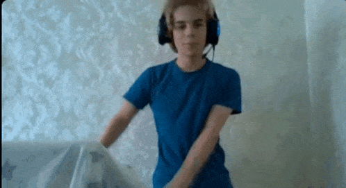 a young boy wearing headphones and a blue shirt is standing in front of a wall .