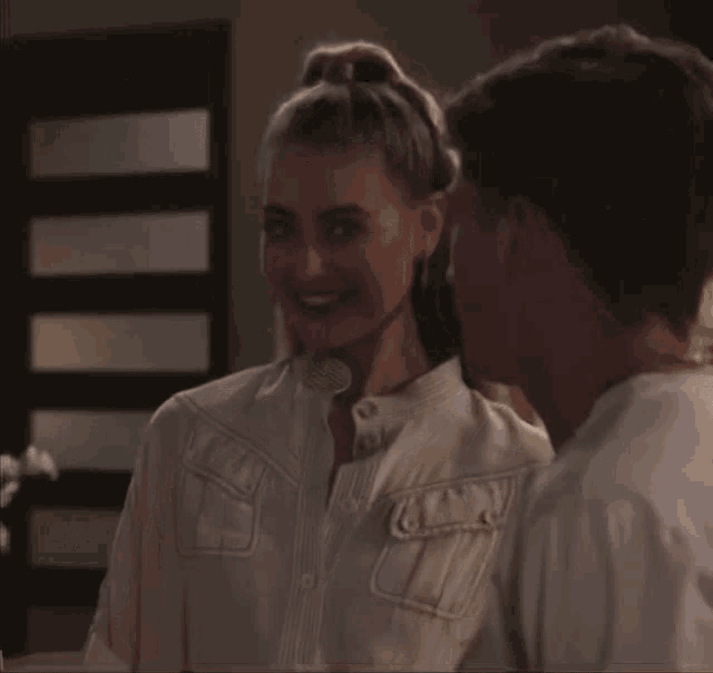 a woman in a white shirt smiles at a man in a white shirt