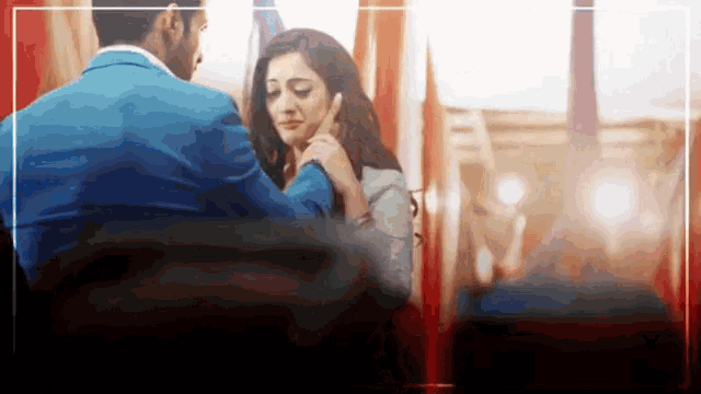 a man in a blue suit is touching a woman 's face in a room .