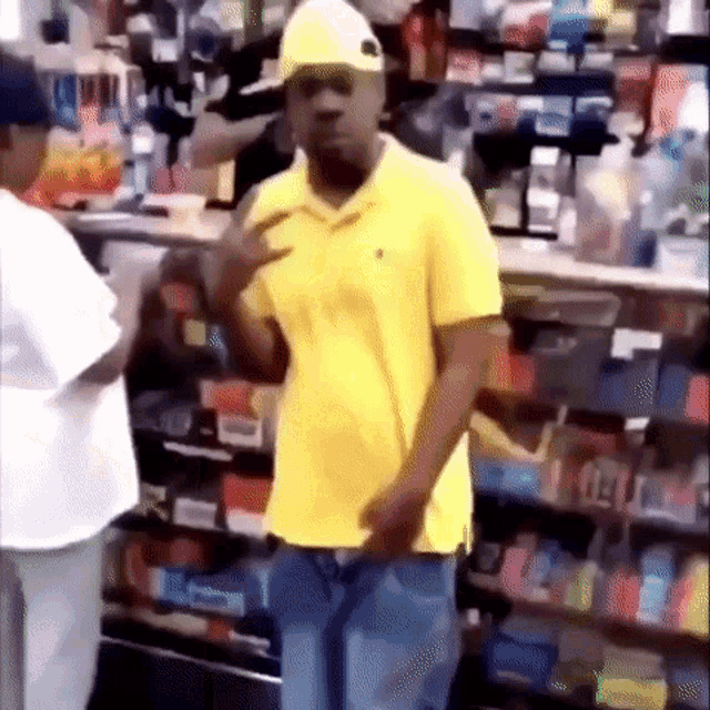 a man in a yellow shirt and white hat is standing in a store .