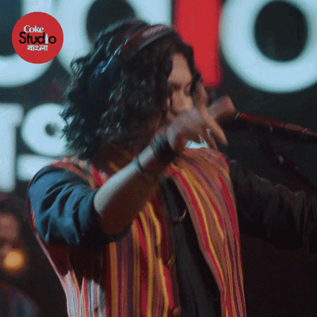 a man is singing into a microphone with a coke studio logo in the background