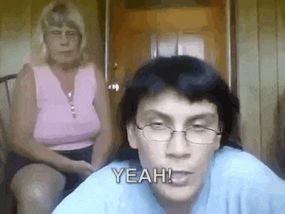 a woman is sitting in a chair behind a man wearing glasses and a woman in a pink shirt .