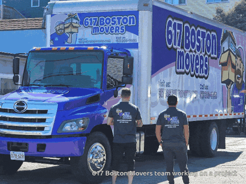 two men are standing in front of a blue and white truck that says 617 boston movers