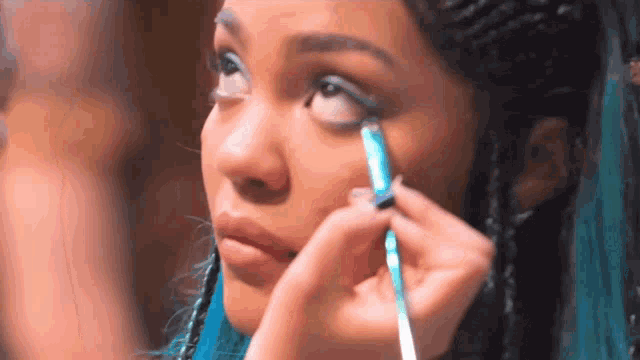 a woman with blue hair is getting her eye makeup done