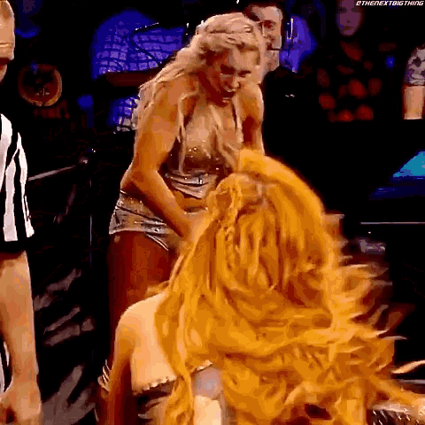 a couple of women are standing next to each other on a stage with a referee in the background .