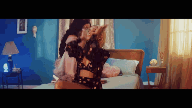 two women dancing on a bed in a bedroom