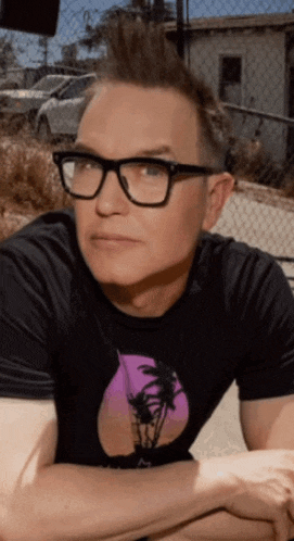 a man wearing glasses and a black t-shirt with a palm tree on it