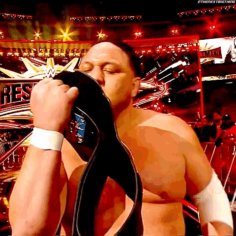 a shirtless wrestler is kissing his belt in front of a sign that says " rest "