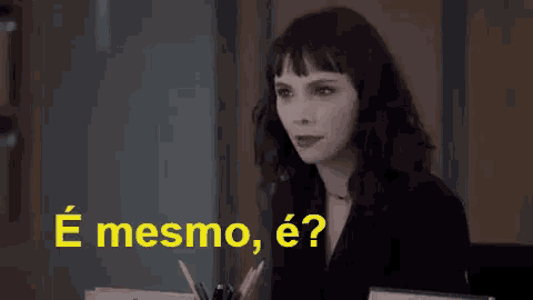 a woman sitting at a desk with the words " e mesmo e " written in yellow