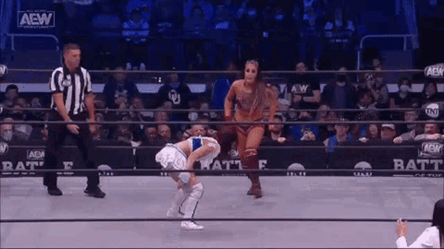 a woman is standing in a wrestling ring with a referee .