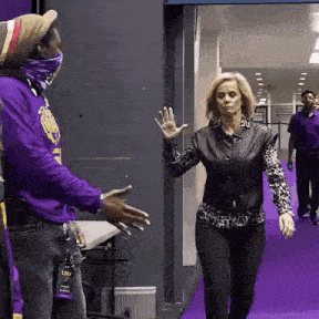 a man in a purple shirt is shaking hands with a woman in a leopard print shirt .