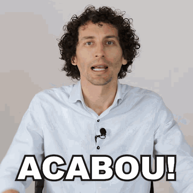 a man with curly hair says " acabou " in front of a microphone