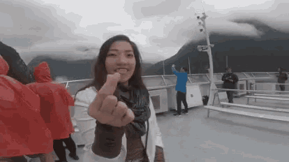 a woman giving the middle finger while standing on a boat
