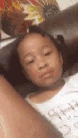a little girl is laying on a couch and making a funny face