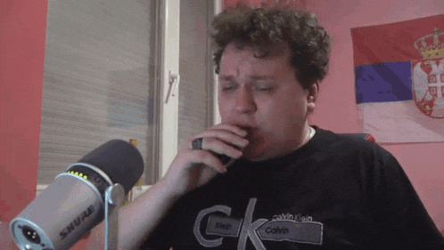 a man singing into a shure microphone in front of a calvin klein shirt