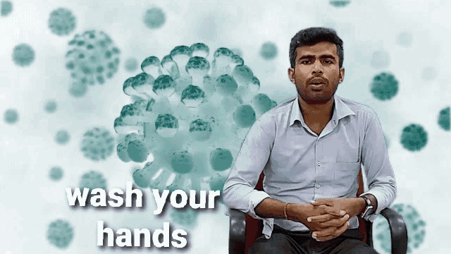 a man is sitting in front of a graphic that says wash your hands