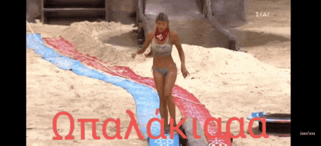 a woman in a bikini is walking across a blue and red carpet with the word otalakioa in red