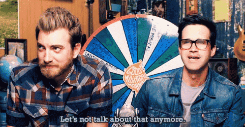 two men are standing in front of a spinning wheel and one of them says let 's not talk about that anymore