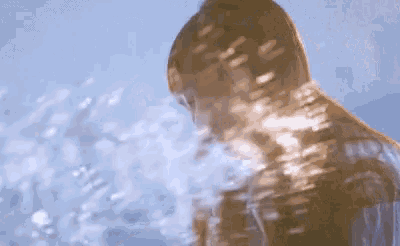 a woman stands in front of a body of water with her eyes closed