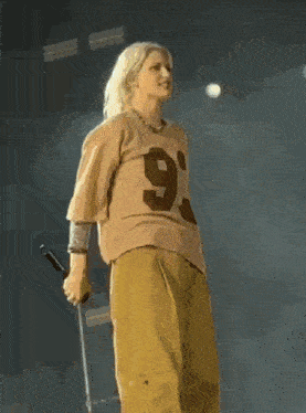 a woman is singing into a microphone on a stage while wearing a number 9 shirt .