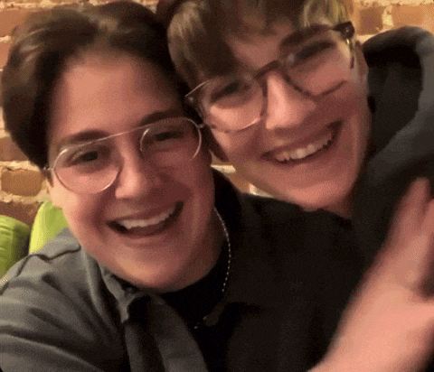 two people wearing glasses are hugging and smiling for a picture