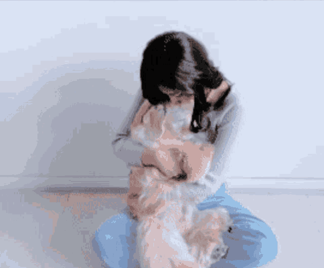 a woman sitting on the floor hugging a small brown dog