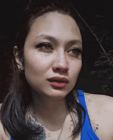 a close up of a woman 's face with a tattoo on her arm