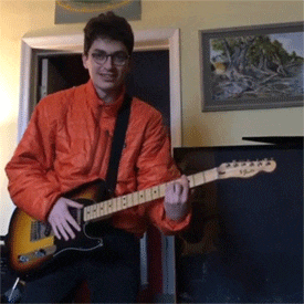 a man in an orange jacket is holding a guitar