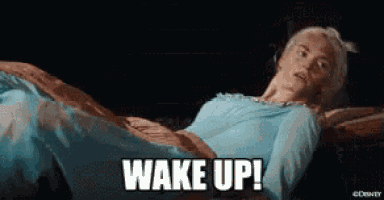 a woman in a blue dress is laying in bed with the words `` wake up '' above her .