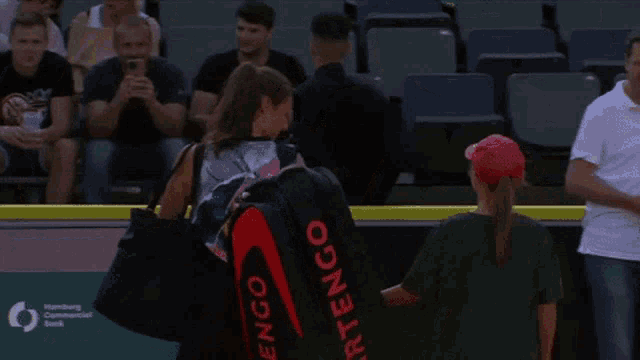 a woman carrying a tennis bag that says " artengo "
