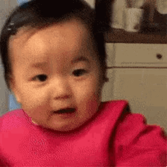 a baby girl in a pink bib is making a funny face .