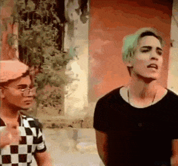 a man with green hair is standing next to another man with black hair .