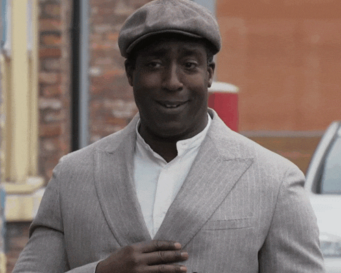 a man wearing a hat and a gray suit is smiling