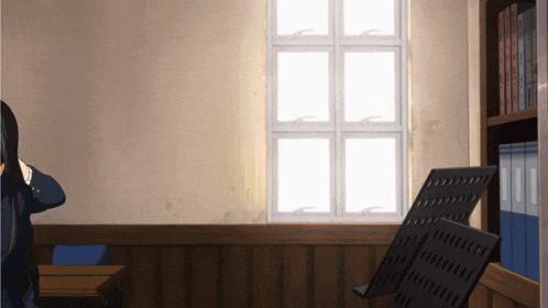 a person standing in front of a window in a room with binders on the shelf