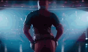 a man in a deadpool costume is standing on a stage with his hands on his hips and looking at the camera .
