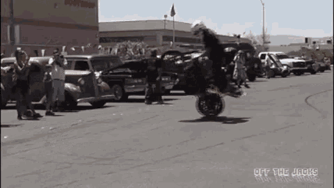 a man is doing a trick on a motorcycle in front of a crowd of people .