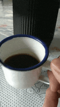 a cup of coffee with a blue rim and handle