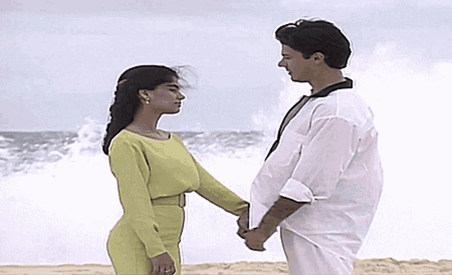 a man and woman are holding hands on the beach