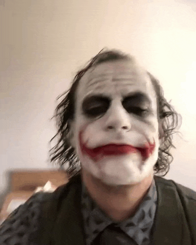 a man in a suit and tie is wearing a joker mask on his face .