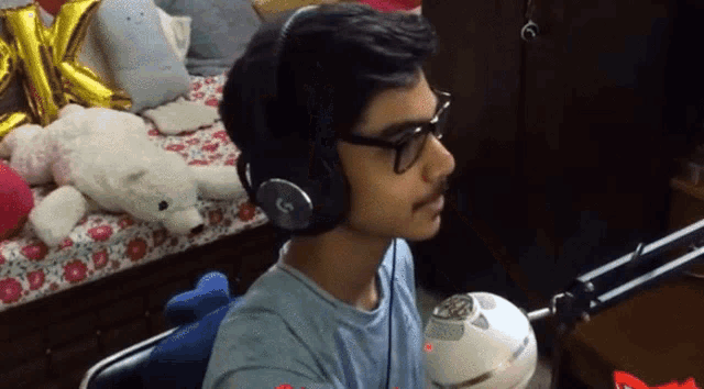 a young man wearing headphones and glasses is sitting on a bed