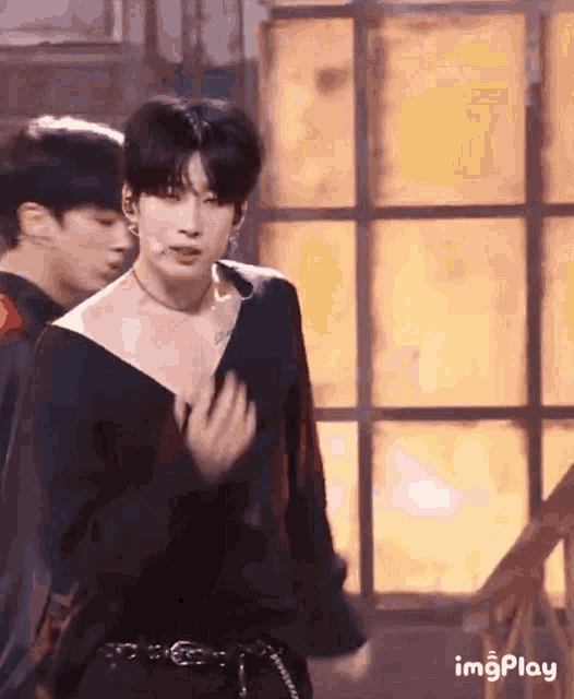 a man wearing a black off the shoulder top is dancing on stage .