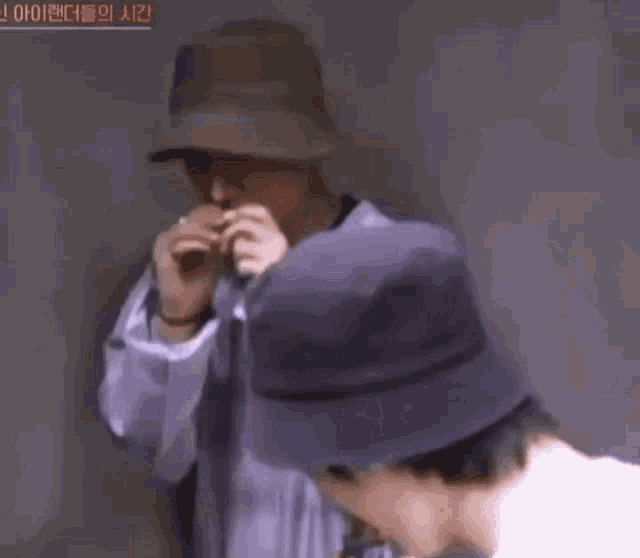 a man wearing a hat and a purple jacket is eating a piece of food .
