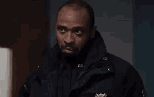 a man in a police uniform is talking to another man in a dark room .