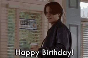 a man in a leather jacket is holding a cup of coffee and says `` happy birthday '' .