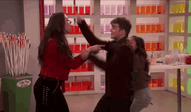 a man and a woman are fighting in front of a display of lollipops that say like you a lot